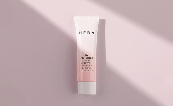 HERA UV Protector Tone-Up sunscreen tube with SPF 50 and pink gradient packaging on pale pink background