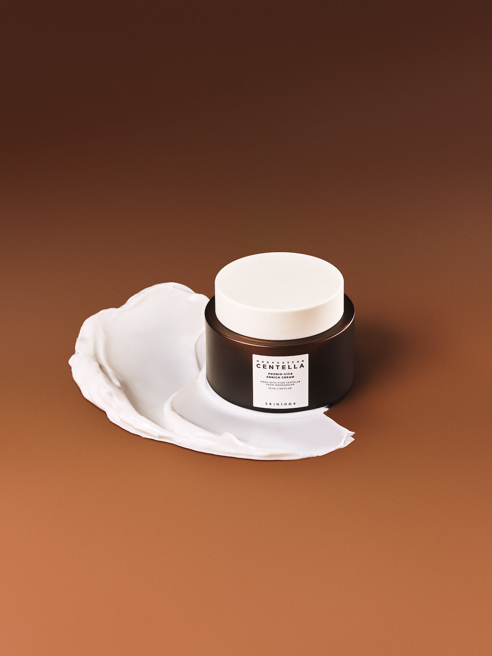 Madagascar Centella Probio-Cica Enrich Cream 50ml in jar with cream smear on brown background
